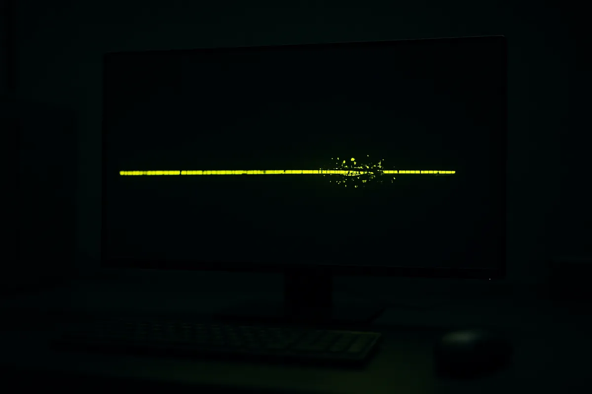 A dark screen showing a green line of code with one section fracturing apart while the rest stays intact.
